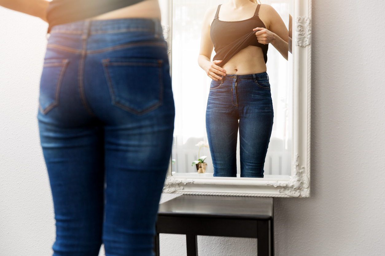 Woman checking her body image in mirror